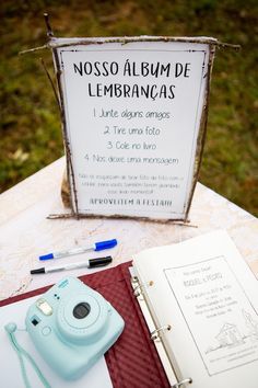 a camera and notebook sitting on top of a table next to a sign that says nosso album de lembancaas