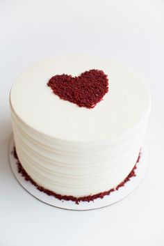 a white cake with red sprinkles in the shape of a heart on top