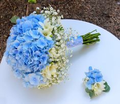 a bouquet of blue and white flowers sitting on top of a table next to another bouquet