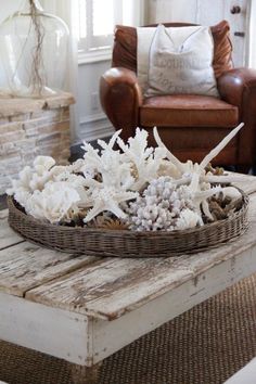 a basket with white flowers sitting on top of a wooden table in front of a chair