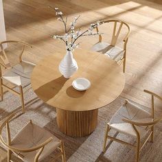 a wooden table with chairs around it and a white vase on the table top in front of it