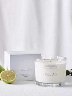 a white candle sitting on top of a table next to a slice of lime and a box