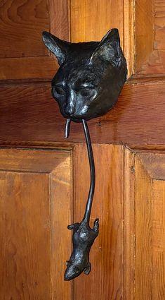 a metal cat head mounted to the side of a wooden door