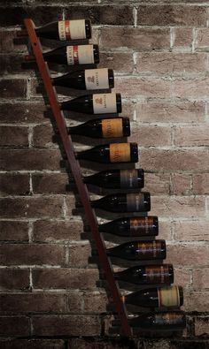 several bottles of wine are lined up against a brick wall with a ladder to reach them