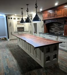 a large kitchen island with two pendant lights hanging from it's ceiling and an oven in the background