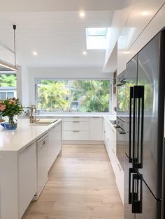 a modern kitchen with white cabinets and stainless steel appliances, along with wood flooring