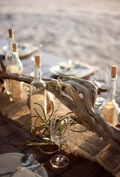 an outdoor table set up with wine bottles and plates