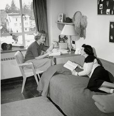 two women sitting on a bed reading books