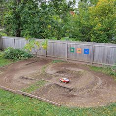 a dirt track in the back yard with a toy car on it's side