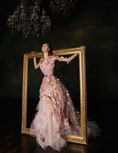 a woman standing in front of a framed photo wearing a pink dress with flowers on it