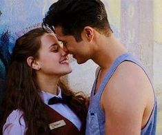 a man and woman standing next to each other in front of a graffiti covered wall