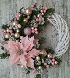 a christmas wreath with poinsettis, pine cones and pink balls on it