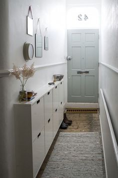 a hallway with white cabinets and a gray door