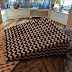 a black and white blanket sitting on top of a bed in a bedroom next to a window