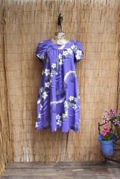 Hilo Hattie Vintage Floral Hawaiian Cotton Dress. Bright and vibrant! This vintage flowing Hawaiian Mumu style dress by The Hawaiian Original is bursting with white plumeria flowers, green and black fern pattern on a dusty lavender. Perfect for a tiki party or any summer day at the beach. It has a side pocket. Adorable scalloped sleeves.  Made in the Hawaii B: 38" W:40" H:58" L: 40 Hawaiian Mumu Dress, White Plumeria Flowers, Mrs Roper, White Plumeria, Scalloped Sleeves, Fern Pattern, Dusty Lavender, Plumeria Flowers, Mumu Dress