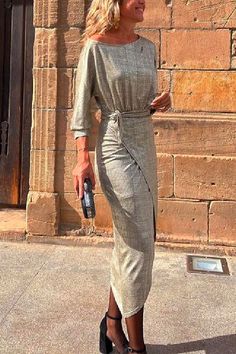 a woman walking down the street in a gray dress