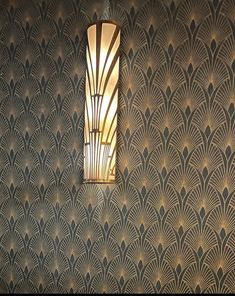 an art deco light fixture hangs on the wall next to a patterned wallpaper pattern