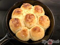 a cast iron skillet filled with bread rolls on top of a stove burner