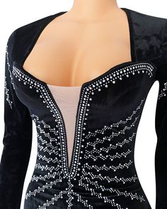 a woman wearing a black and white dress with beading on the shoulders, in front of a mannequin