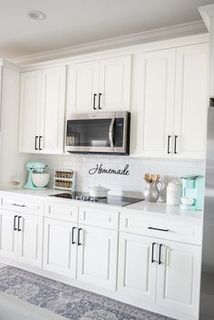 a kitchen with white cabinets and silver appliances