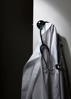 a stethoscope hanging from the side of a white coat on a wall