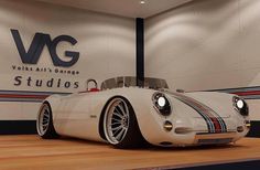 a white sports car sitting on top of a hard wood floor next to a wall