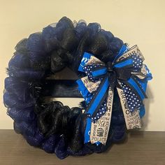 a blue and black mesh wreath with dollar bills tied to it on a wooden table