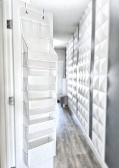 an empty hallway with white storage bins hanging on the wall and wood flooring