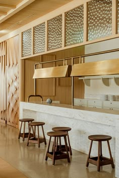 an empty kitchen with stools in front of the counter