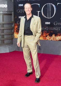 a man in a tan suit and black shirt at the game of thrones premiere