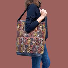 a woman carrying a multicolored handbag on her left shoulder and the back of her right arm