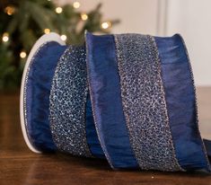 a roll of blue glitter ribbon sitting on top of a table next to a christmas tree