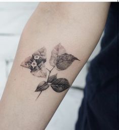 a woman's arm with a tattoo on it that has leaves and flowers on it