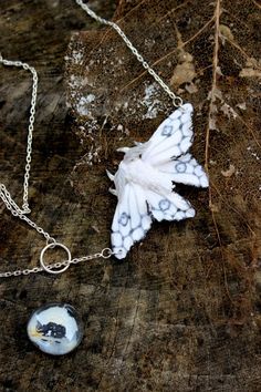 two necklaces with white and blue designs on them sitting on a rock next to a leaf