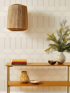 a wooden table topped with a vase next to a plant and a lamp shade on top of it