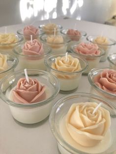 small cupcakes are arranged in glass bowls on a white counter top with candles