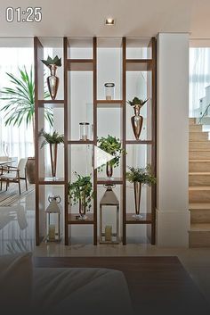 a living room filled with lots of furniture next to a stair case covered in plants