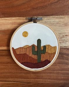 an embroidered desert scene with a cactus in the foreground