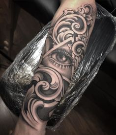 an eye tattoo on the arm with swirls and waves in black and grey colors