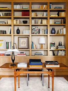 an office with bookshelves and desk in front of the bookcases is shown