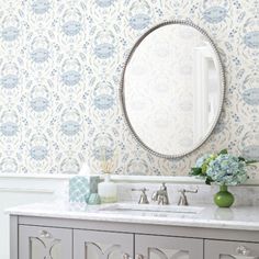 a bathroom vanity with a mirror above it and flowers in vases on the counter