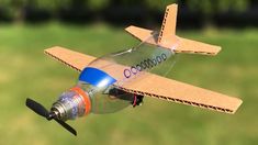 an airplane made out of cardboard sitting on top of a grass covered field