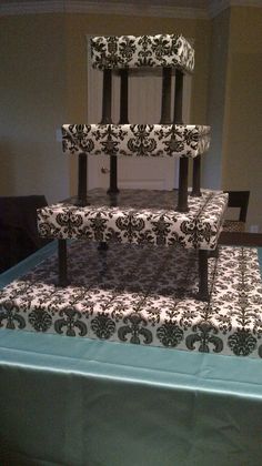 a three tiered cake sitting on top of a table covered in black and white damask