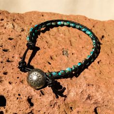 Created by the artists at Alta Studios this Turquoise Bead and Leather Wrap bracelet is hand crafted high in the mountains of Northern New Mexico. Made from genuine high quality turquoise saucer beads, black Greek leather cord and cast metal "sun shield" button. A beautiful piece of the Southwest! This item is one of a kind - you will receive the exact item pictured. Adjustable length : Approx. 7" to 7 1/2" dia. 12 oz. Shipping Weight Nickel-free Turquoise Beaded Bracelets For Festivals, Adjustable Turquoise Wrap Bracelet For Festival, Southwestern Adjustable Hand Wrapped Jewelry, Adjustable Southwestern Hand Wrapped Jewelry, Southwestern Hand Wrapped Adjustable Jewelry, Adjustable Southwestern Style Hand Wrapped Jewelry, Handmade Turquoise Leather Bracelet Spiritual, Southwestern Style Turquoise Leather Bracelet For Festivals, Adjustable Leather Bracelet With Round Beads