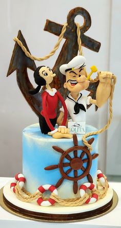 there is a cake that looks like an anchor and sailor on the ship with two people