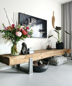 a wooden table with vases and flowers on it in front of a large window