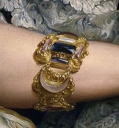 a woman's arm with gold jewelry on it