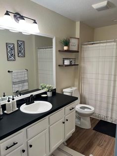 a bathroom with black counter tops and white cabinets