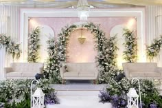 an outdoor wedding setup with white flowers and greenery on the wall, couches and chairs