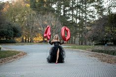 a woman in a black dress holding two red balloons